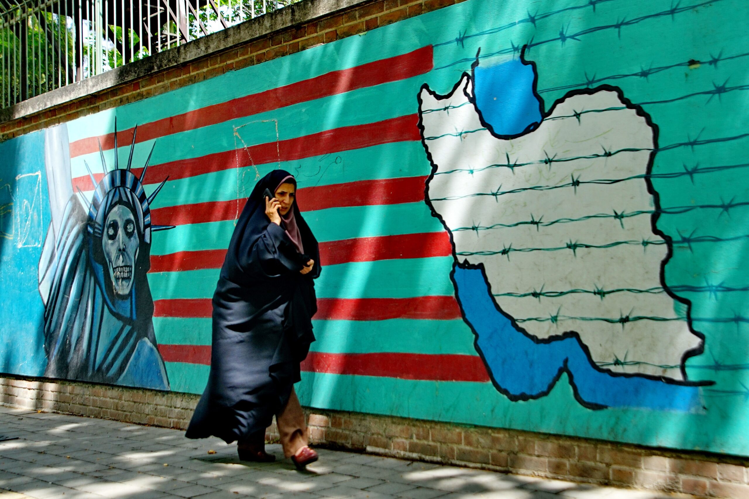 A,Muslim,Woman,Walks,Past,An,Anti american,Mural,On,The